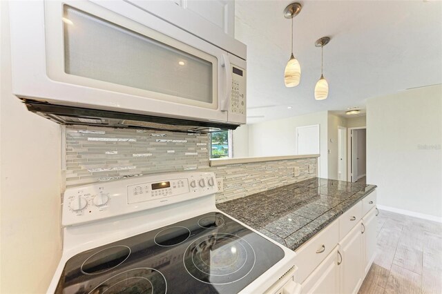 kitchen featuring white cabinets, backsplash, light hardwood / wood-style flooring, pendant lighting, and white appliances