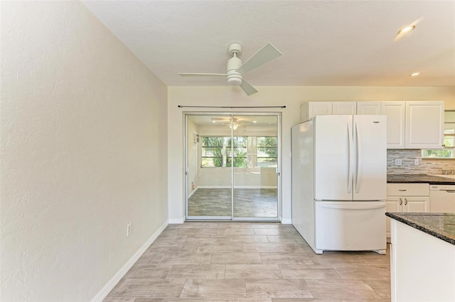 kitchen featuring white appliances, tasteful backsplash, ceiling fan, dark stone counters, and white cabinets