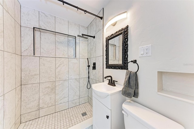 bathroom with toilet, vanity, and a tile shower