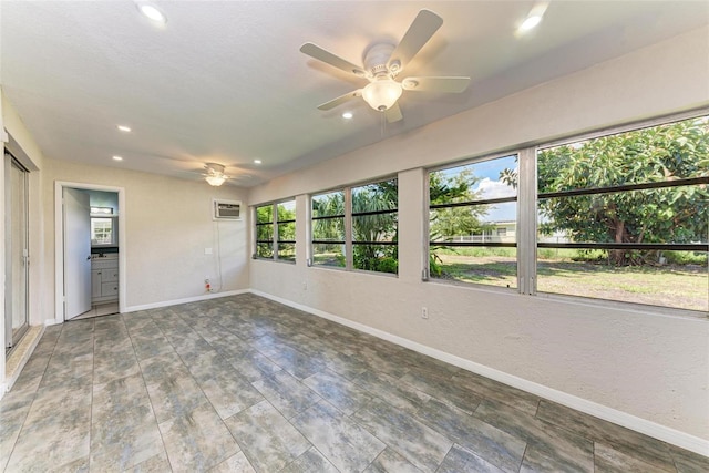 spare room featuring an AC wall unit and ceiling fan