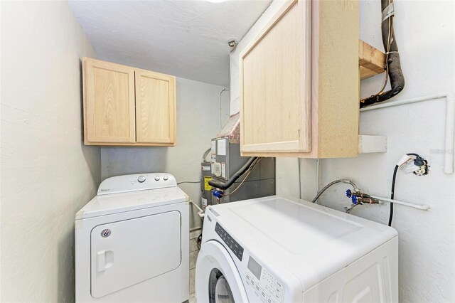 laundry area featuring a textured ceiling, washing machine and dryer, and cabinets