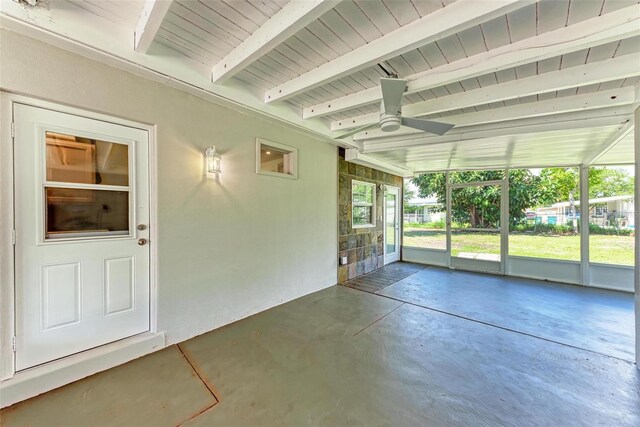 unfurnished sunroom featuring beamed ceiling and ceiling fan