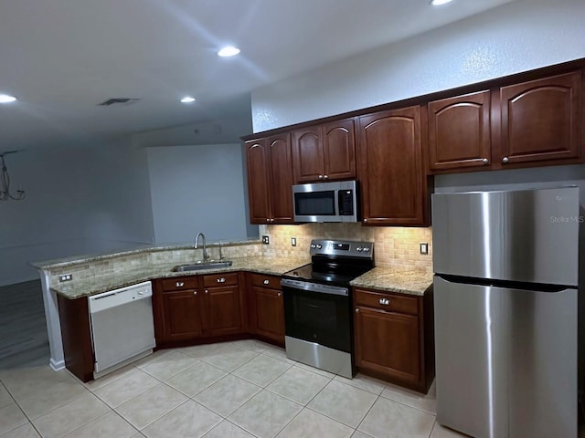 kitchen featuring appliances with stainless steel finishes, kitchen peninsula, light stone countertops, light tile patterned floors, and sink