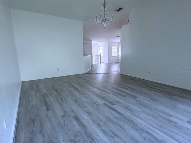 spare room featuring light wood-type flooring and a chandelier