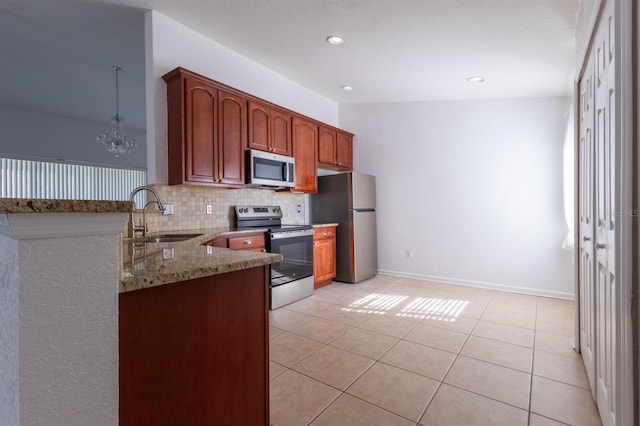 kitchen featuring sink, appliances with stainless steel finishes, light stone countertops, decorative backsplash, and kitchen peninsula