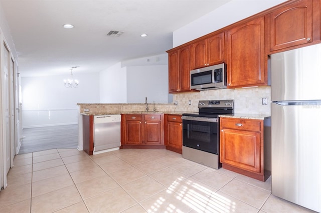 kitchen with appliances with stainless steel finishes, tasteful backsplash, sink, light tile patterned floors, and an inviting chandelier