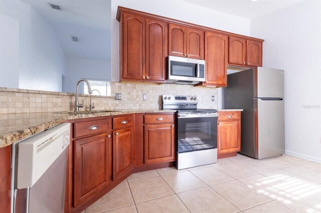 kitchen with sink, decorative backsplash, light tile patterned floors, stainless steel appliances, and light stone countertops