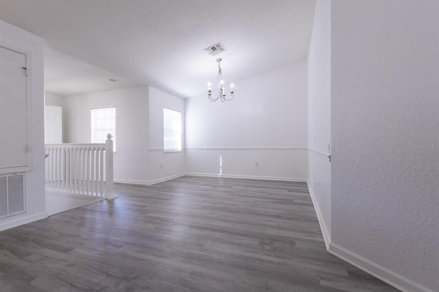 spare room featuring dark hardwood / wood-style floors and a notable chandelier