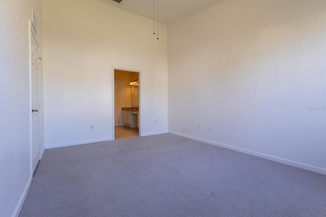 carpeted empty room with a high ceiling