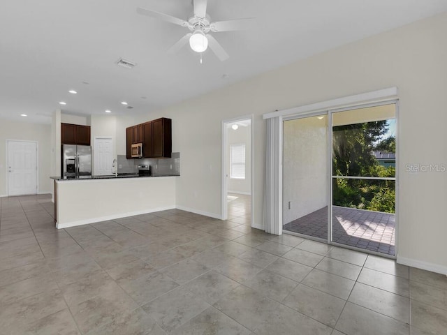 unfurnished living room featuring ceiling fan, sink, and light tile patterned floors