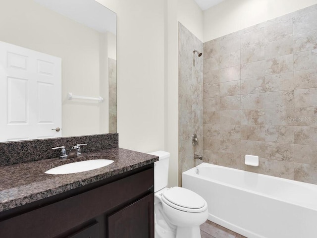 full bathroom featuring tiled shower / bath, vanity, and toilet