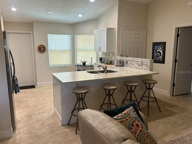 kitchen featuring white cabinets, a textured ceiling, kitchen peninsula, and a breakfast bar area