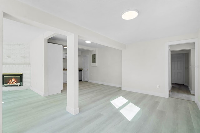 unfurnished living room with electric panel, a fireplace, and light hardwood / wood-style floors