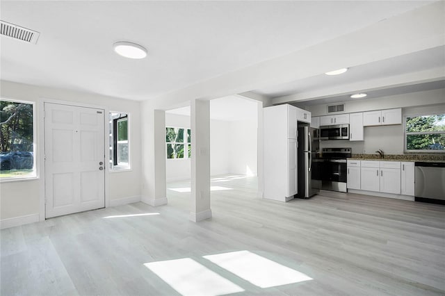 interior space featuring stainless steel appliances, white cabinetry, sink, and light wood-type flooring