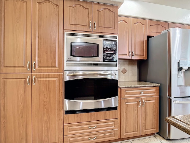 kitchen featuring appliances with stainless steel finishes, light tile patterned floors, and decorative backsplash