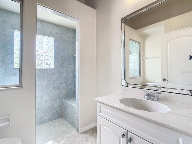 bathroom with tiled shower, tile patterned floors, vanity, and toilet