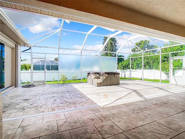 view of patio featuring glass enclosure and a hot tub