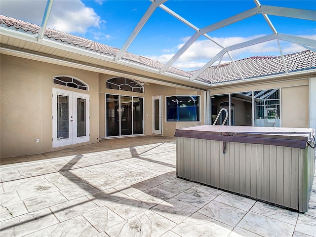 view of patio with glass enclosure and a hot tub