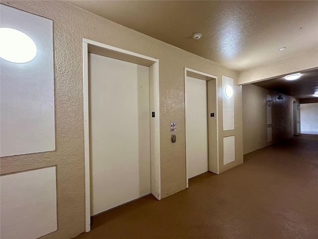 hall featuring a textured ceiling and elevator