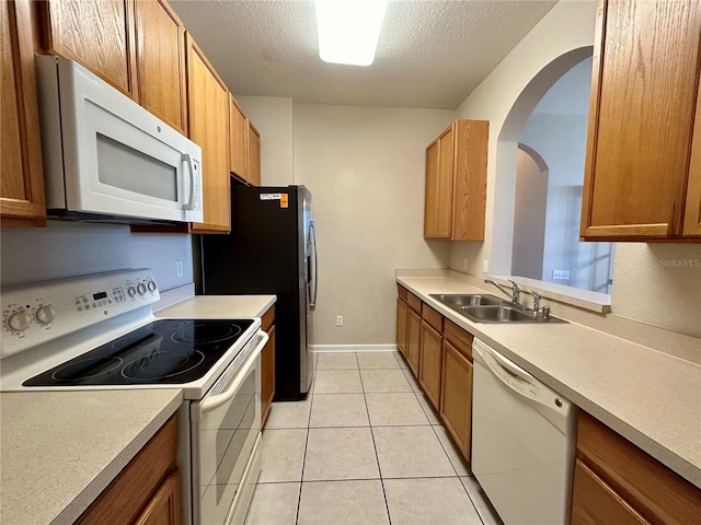 kitchen featuring white appliances, a textured ceiling, light tile patterned floors, and sink