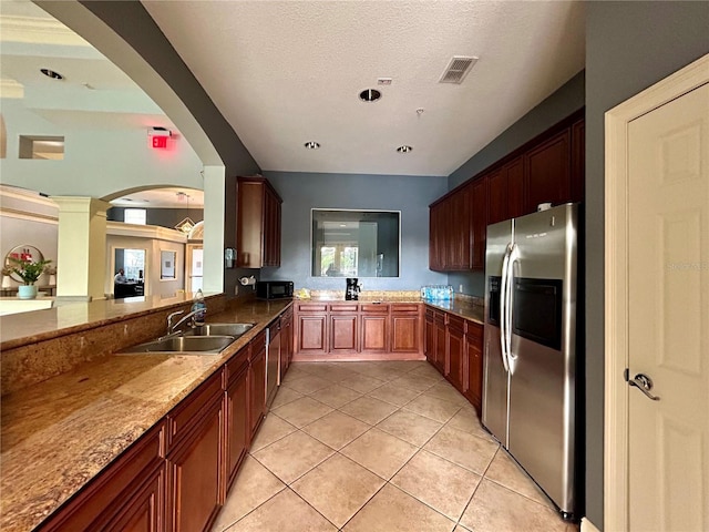 kitchen with stainless steel refrigerator with ice dispenser, light tile patterned floors, a textured ceiling, and stone countertops