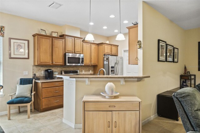 kitchen with sink, kitchen peninsula, backsplash, appliances with stainless steel finishes, and a kitchen breakfast bar