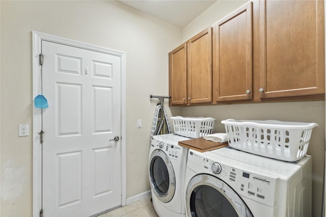 clothes washing area featuring cabinets, washer and dryer, and light tile patterned flooring