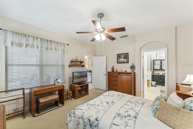 carpeted bedroom with ensuite bath and ceiling fan