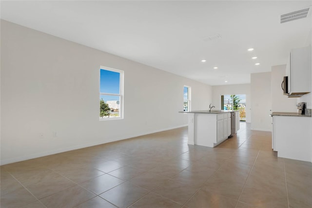 unfurnished living room featuring light tile patterned flooring, a healthy amount of sunlight, and sink