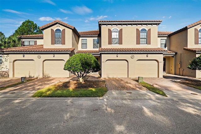 8091 Brooksville Dr, Davenport, FL 33896 - mediterranean / spanish-style house featuring a garage, stucco siding, decorative driveway, and a tiled roof