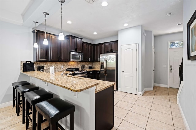 kitchen featuring light stone countertops, appliances with stainless steel finishes, kitchen peninsula, decorative light fixtures, and decorative backsplash