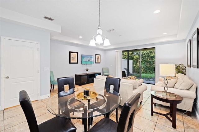 tiled dining room featuring a notable chandelier and a raised ceiling