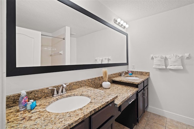 bathroom featuring vanity, a textured ceiling, a shower with shower door, and tile patterned floors