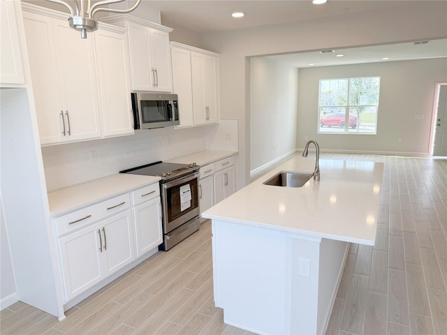 kitchen featuring sink, white cabinetry, stainless steel appliances, a kitchen island with sink, and decorative backsplash