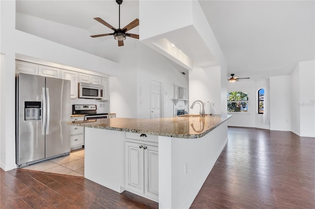 kitchen with white cabinetry, hardwood / wood-style flooring, vaulted ceiling, and appliances with stainless steel finishes