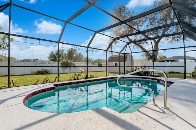 view of pool with a lawn, glass enclosure, a patio area, and a storage unit