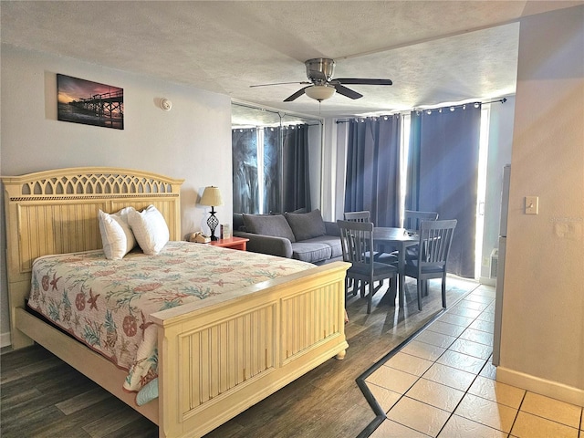 bedroom with a textured ceiling, wood-type flooring, and ceiling fan