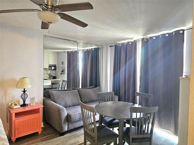 dining room featuring ceiling fan, a textured ceiling, and hardwood / wood-style floors