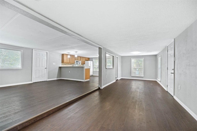 unfurnished living room featuring dark hardwood / wood-style floors and a wealth of natural light