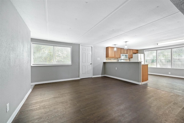 unfurnished living room with dark hardwood / wood-style flooring and plenty of natural light