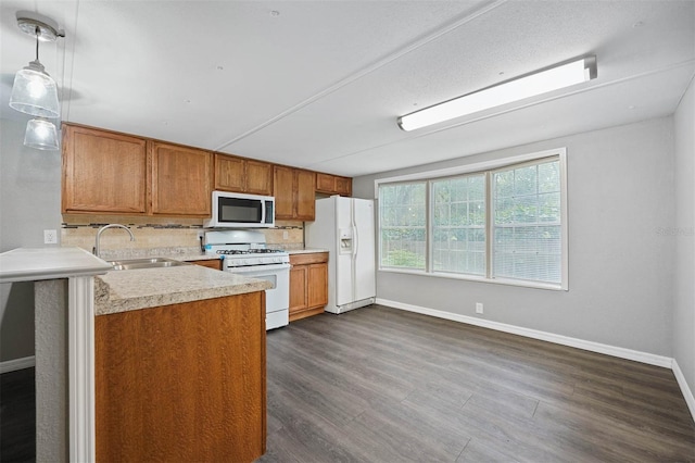 kitchen with white appliances, sink, pendant lighting, and dark hardwood / wood-style flooring