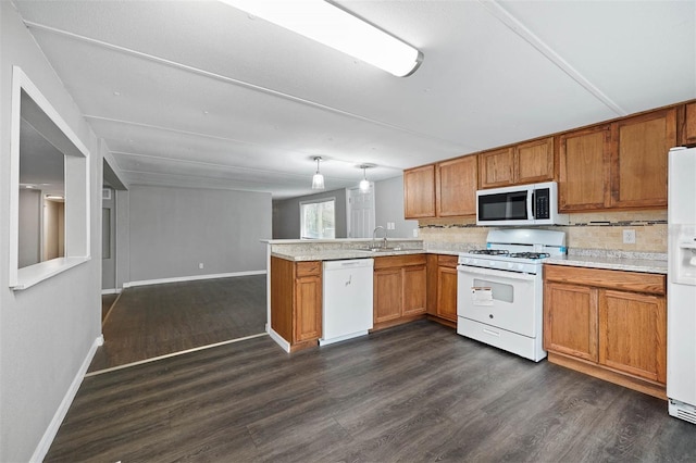 kitchen featuring white appliances, kitchen peninsula, hanging light fixtures, and dark hardwood / wood-style flooring