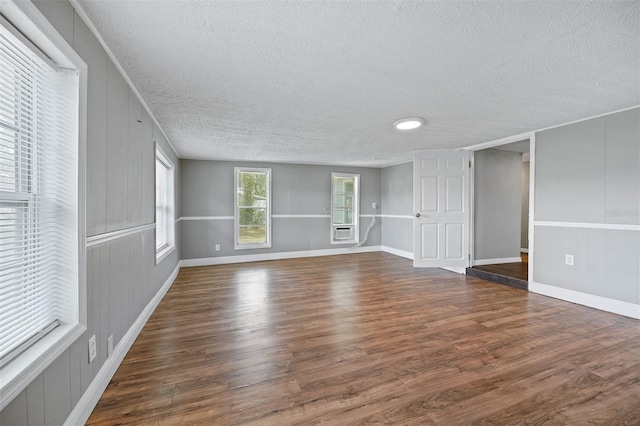 unfurnished living room with cooling unit, a textured ceiling, and dark wood-type flooring