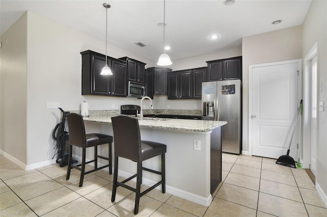 kitchen featuring light stone counters, sink, light tile patterned flooring, pendant lighting, and appliances with stainless steel finishes