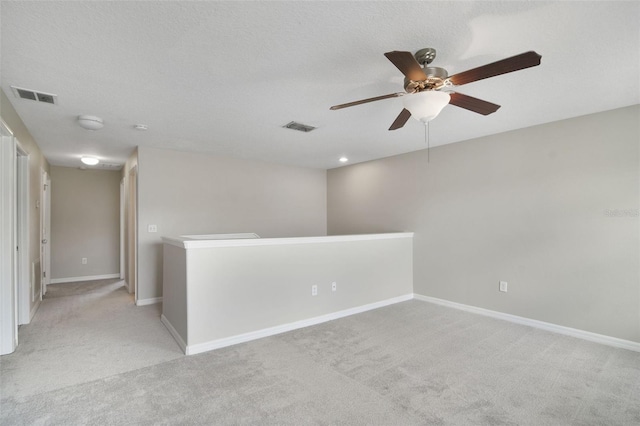 carpeted empty room featuring ceiling fan and a textured ceiling