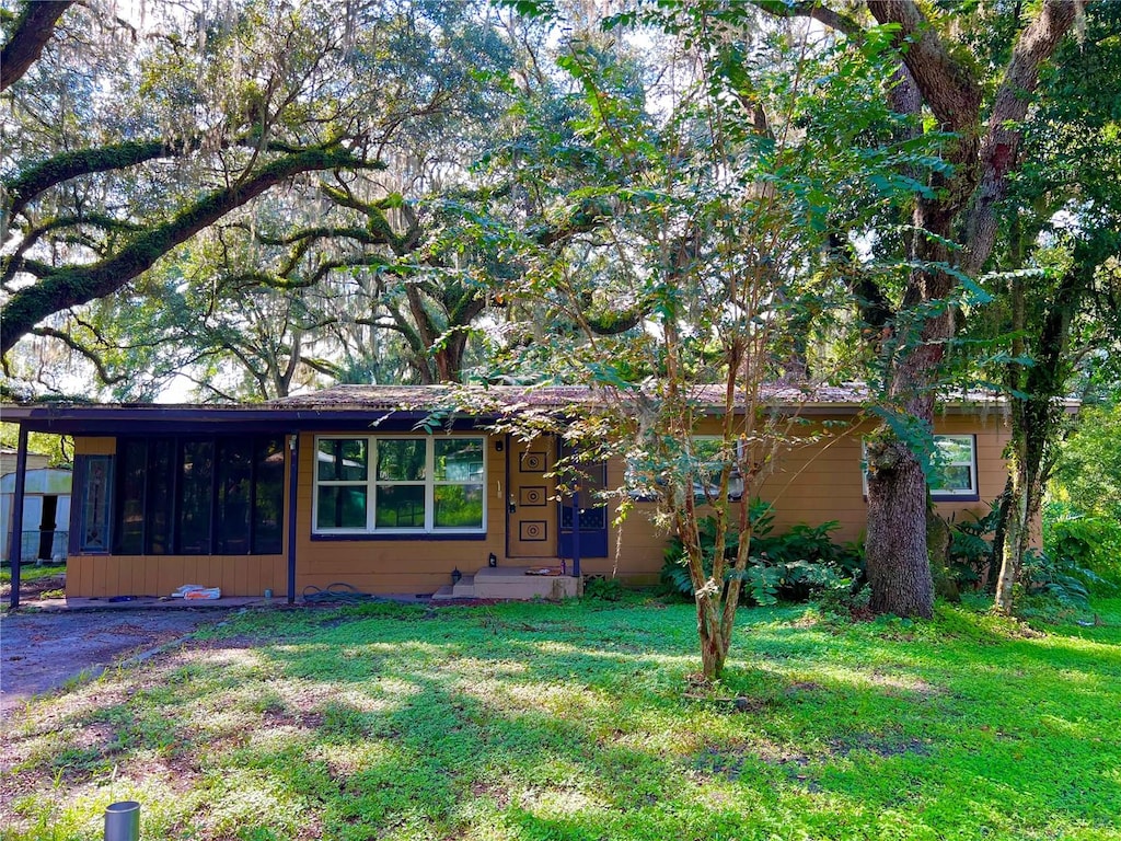 view of front of home featuring a sunroom and a front lawn