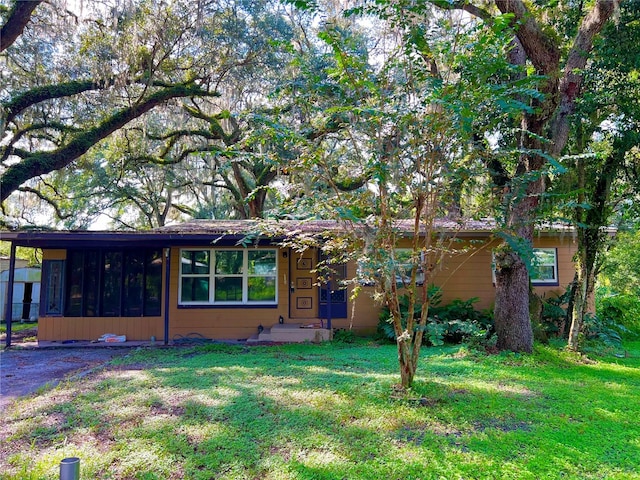 view of front of home featuring a sunroom and a front lawn