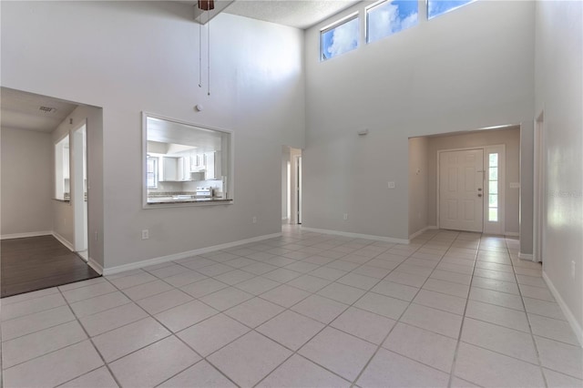 tiled entryway featuring a textured ceiling, a high ceiling, and a wealth of natural light