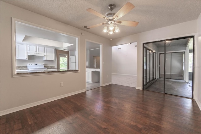 spare room with a textured ceiling, ceiling fan, and dark hardwood / wood-style flooring