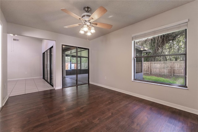 spare room featuring a textured ceiling, wood-type flooring, and a wealth of natural light